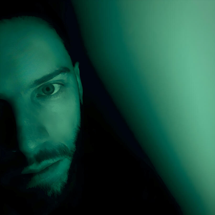 Eric's face in shadowy dark green lighting